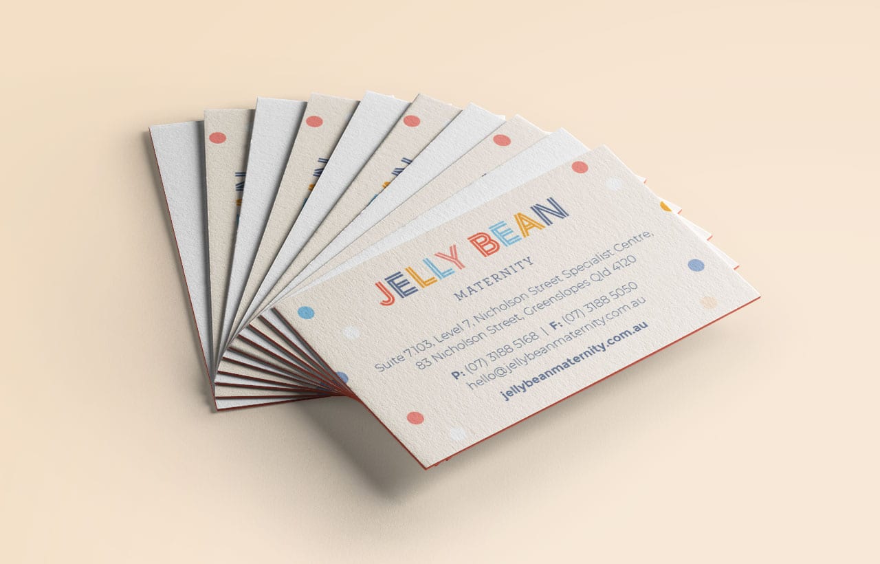 A stack of Jelly Bean Maternity business cards displayed in a fan arrangement on a neutral surface. The cards feature colourful text and pastel polka dots.